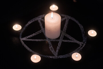 Pentagram and burning candles. The magical ritual of Satanism, invocation of spirits,...
