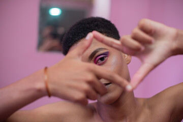 Portrait of young queer male watching through his fingers