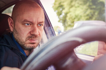 A man focused at the wheel of a car.