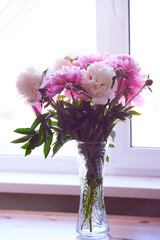 White and pink peonies are in a vase on the table. Large flowers grown on your home lawn