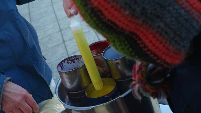 Girl covering candles with hot wax at a Christmas market