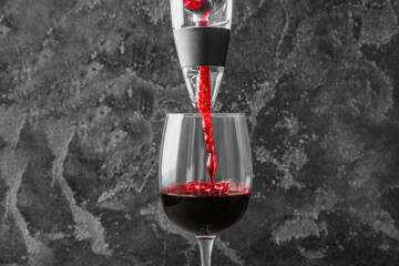 Pouring of wine from aerator into glass on dark background
