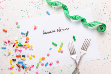 Paper sheet with text ANOREXIA NERVOSA, pills, forks and measuring tape on white background