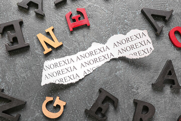 Piece of paper with text ANOREXIA on grey background