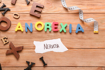 Text ANOREXIA NERVOSA with measuring tape on wooden background