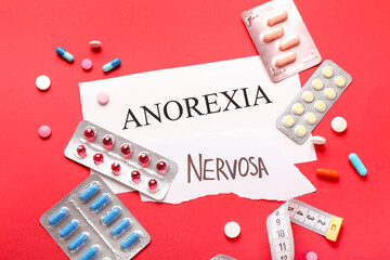 Text ANOREXIA NERVOSA with pills and measuring tape on color background
