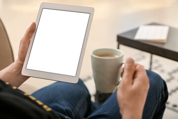 Man with tablet computer drinking coffee at home