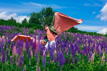Tall handsome man standing on lupine flowers field with pink cloth