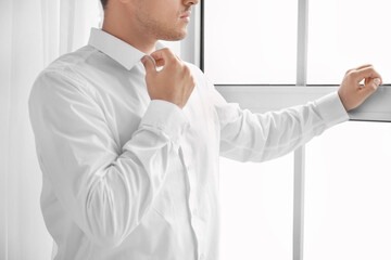 Naklejka na ściany i meble Young businessman in stylish shirt near window in office
