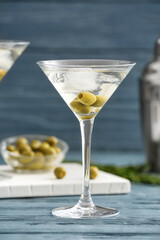 Glass of tasty martini cocktail with olives on table