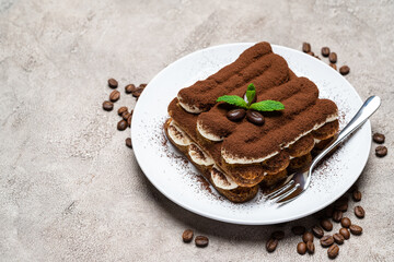 Classic tiramisu dessert on ceramic plate on concrete background
