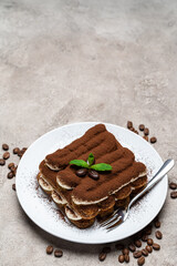 Classic tiramisu dessert on ceramic plate on concrete background