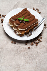Classic tiramisu dessert on ceramic plate on concrete background