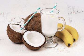 Fresh sweet healthy coconut milkshake with bananas on a wooden table