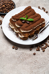 Classic tiramisu dessert on ceramic plate on concrete background