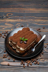 Classic tiramisu dessert on ceramic plate on wooden background
