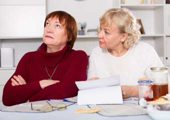 Senior woman explaining document to offended female