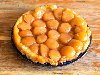 home-made caramelised apple pie Tarte Tatin on old wooden table in home kitchen