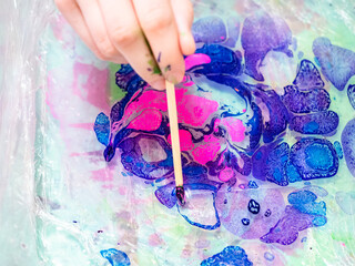 workshop of Ebru paper marbling - mixing of blue and pink dyes on surface of liquid in plastic...