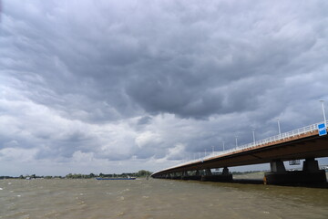 Fototapeta premium Dark clouds above the Moerdijkbrug over water named Hollands Diep.