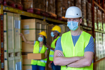 Group warehouse workers wearing protective mask to Protect Against Covid-19 working in industrial factory or warehouse.