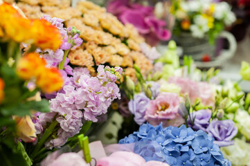 A variety of flowers in the window of a flower shop. Showcase. Stylish bouquets. Small business. Behind the glass. Selective focus.