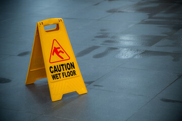 Fototapeta Yellow wet floor caution sign during rain with puddle of water when floor is slippery and copy space for text
 obraz