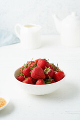 Strawberries in white bowl, on white table, morning Breakfast, summer food