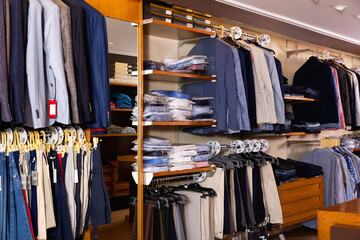 Fashion modern men clothes displayed on shelves and hanger racks in clothing store