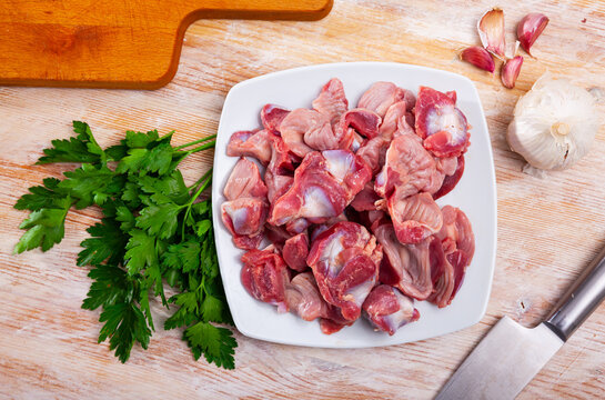 Raw chicken gizzards  before cooking on table with greens
