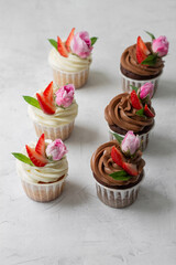 Cupcakes are decorated with strawberries and roses