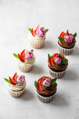 Cupcakes are decorated with strawberries and roses