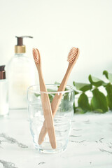 Bamboo toothbrushes are eco-friendly in a glass with a copy of the space on a marble-white background. Zero waste. Free plastic.