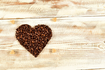 Heart made of coffee beans on wooden table. Top view.