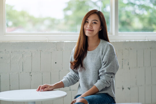 Portrait image of a beautiful young asian woman sitting in cafe with feeling happy