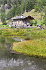 Fototapeta na wymiar alpine cottage at the edge of a water in alpine mountain