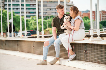 young couple in a bridge with their dog in an urban scene