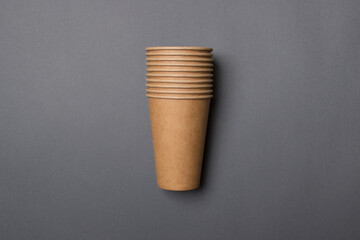 Eco-friendly cardboard cups lie on a gray color paper background. Mock-up. Close-up. The concept of ecology
