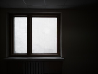 Window overlooking the wall. Silhouette of a window in dark interrior behind which the wall is...