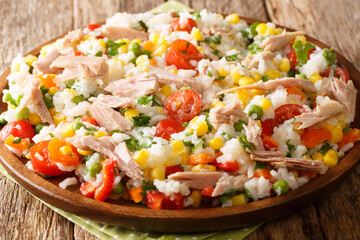 Cooked rice with tuna, tomatoes, sweet pepper, corn, green peas and herbs close-up in a plate on the table. horizontal