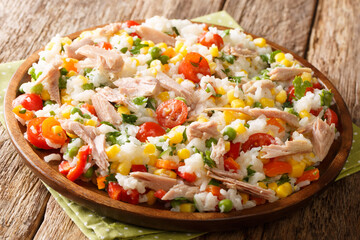Salad of rice, tuna, tomatoes, sweet pepper, corn, green peas and herbs close-up in a plate. horizontal
