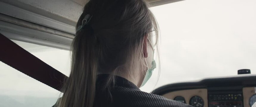 Woman copilot with face mask excited in cockpit of small airplane plane aircraft take off airborne staycation local travel virus covid 19 coronavirus pandemic outbreak new normal