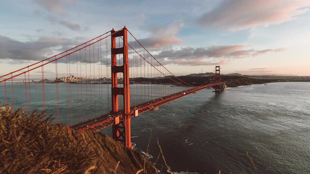 Timelapse of boats in current under traffic on Golden Gate Bridge in sunset