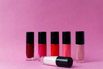 Multi-colored nail polish to create a bright manicure on a pink background.