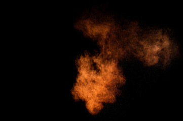 Orange powder explosion on black background. Colored powder cloud. Colorful dust explode. Paint...