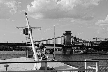 Czarno-biały widok z łodzi na rzece Dunaj na antyczny most łańcuchowy w Budapeszcie - obrazy, fototapety, plakaty