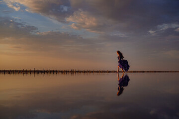 Elegant woman in silky dress walking by a salt lake.