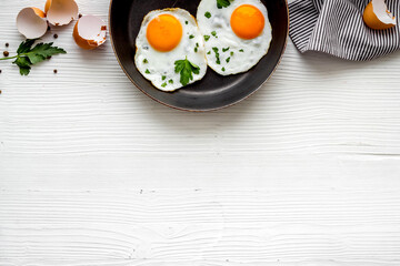 Fried eggs on frying pan - breakfast - on white table from above space for text