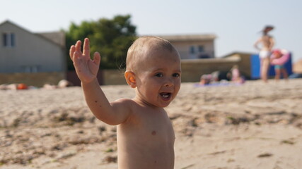 Little boy walking on sea beach with raised hand