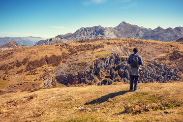 Fototapeta na wymiar A man stays on the top of the mount, looks at the beautiful panorama of the mountains. National Park Peaks of Europe. Cantabria, Spain, Europe